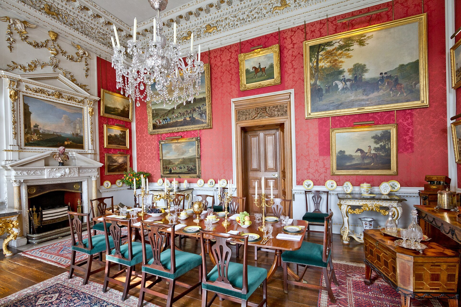Crimson Dining Room with red walls, paintings, chandelier, and long dining table