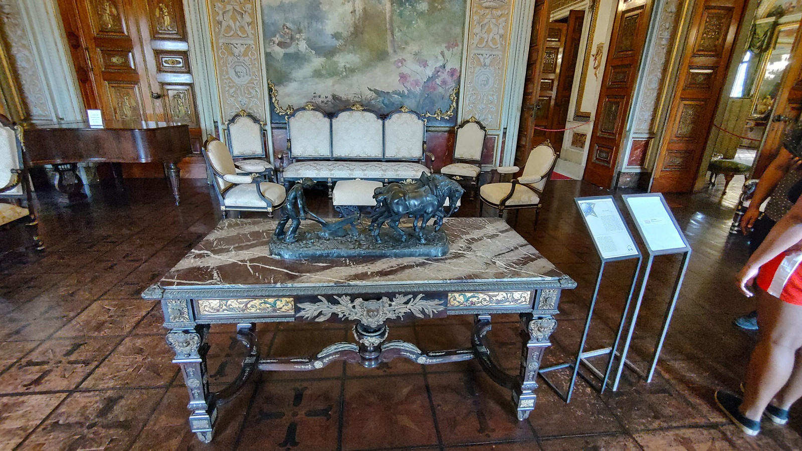 Pale reception room at Palácio do Catete with carved doors, upholstered seating, and a piano