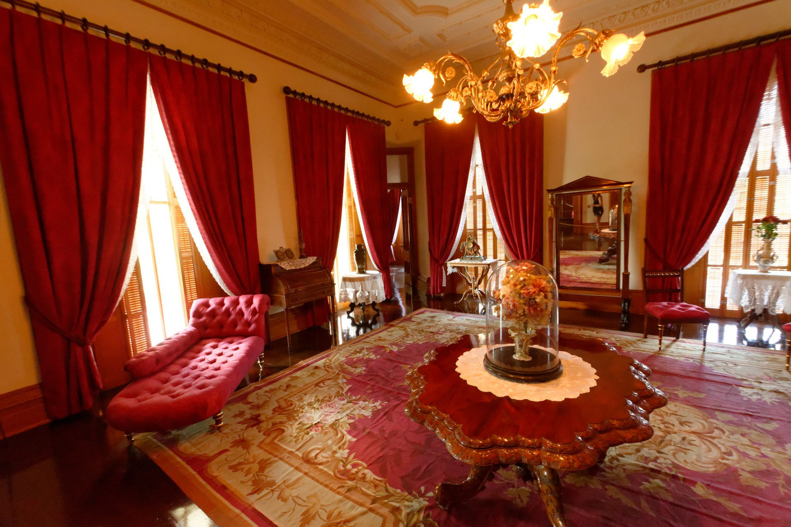 Queen Kapiʻolani’s bedroom with red furnishings, chandelier, and patterned carpet