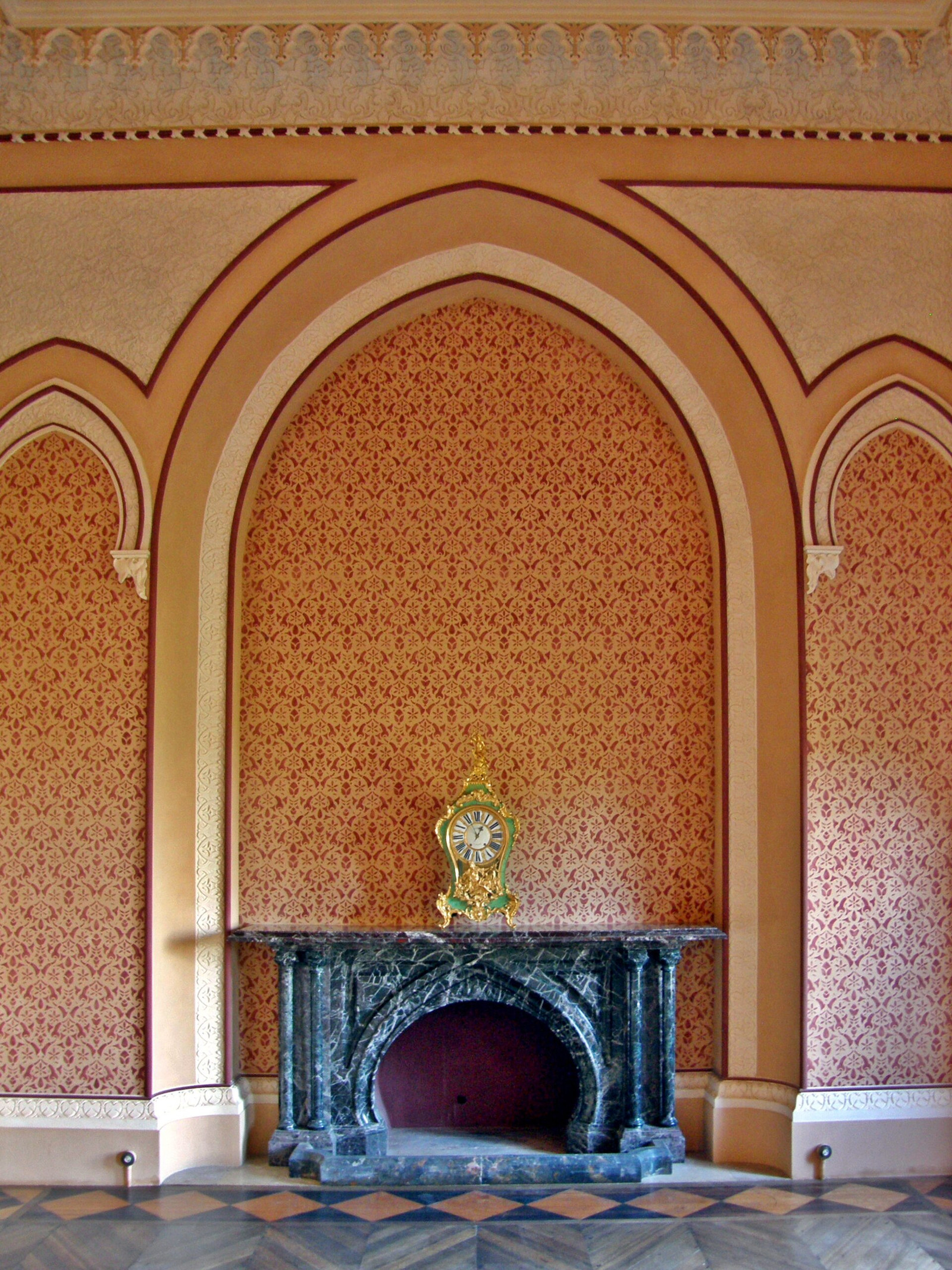 East-wing room at Monserrate with pointed arches, patterned walls, and a dark marble fireplace