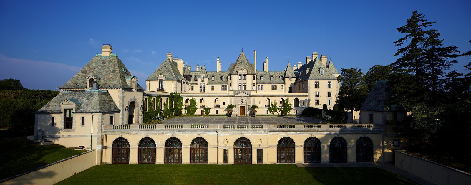 Oheka Castle courtyard framed by long arched galleries and steep slate roofs