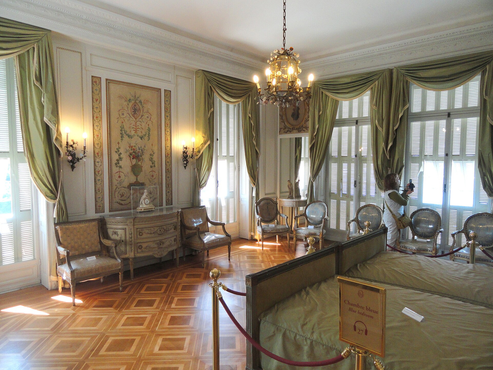 The Blue Room at Villa Ephrussi with parquet flooring, pale paneling, furnished displays, and a chandelier