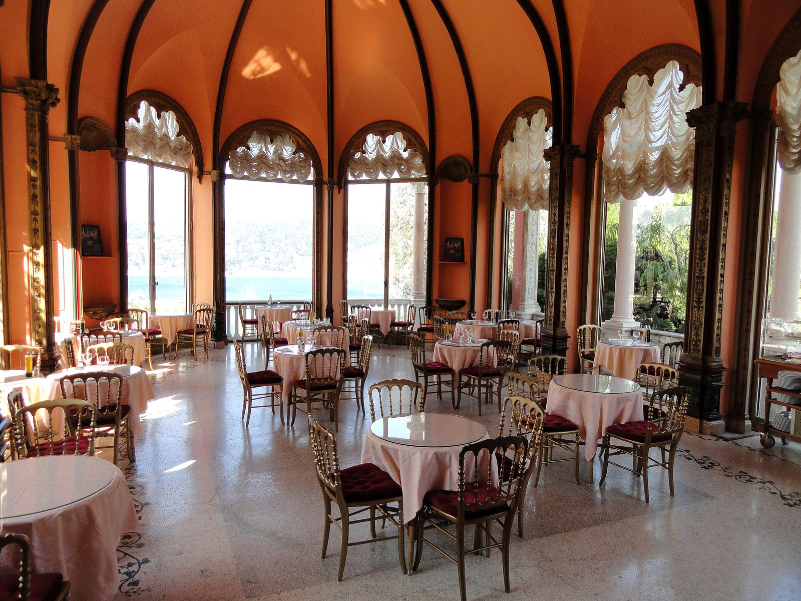 The glazed dining room at Villa Ephrussi with arched windows opening toward the Mediterranean